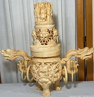 Front view of vintage plastic composite Eastern style dragon incense burner showing dual dragon head handles, carved central body detailing, and lid with standing figures