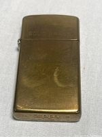 Front view of vintage solid brass Zippo lighter showing engraved 'SOLID BRASS' and tarnish spot.