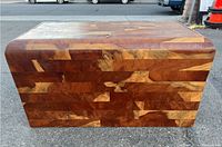 Full view of multi-panel wood storage chest with rounded corners and hinged top lid, showing patchwork of wood segments