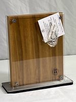 Front and side view of the magnetic cutlery block showing natural Acacia wood behind clear acrylic panels on a metal base with black padding underneath. Includes Schmidt Brothers Cutlery logo.