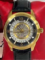 Gold-tone CCCP automatic watch face on red pillow showing skeletonized dial and gold Arabic numerals