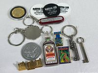Lot showing assorted collectible keychains, pins, coins, pocket tool, and tokens.