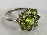 Front view of sterling silver ring with multiple round green peridot stones arranged in floral cluster.