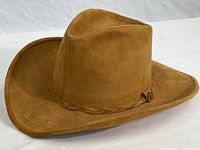 Side view of tan leather cowboy hat showing shape and texture.