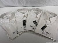 Four white men's dress shirts by Van Heusen in original sealed packaging, all size 16-1/2 neck 32/33 sleeve.