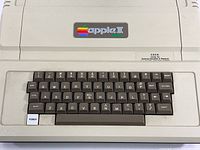 Front of beige Apple II Plus computer showing integrated keyboard and rainbow Apple II logo