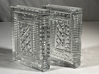 Side view of two solid crystal bookends standing upright, showing ribbed spine detail and cut patterns
