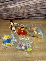 Full lot with six toys shown on wood surface: Aladdin figure, Chipmunks, Daffy Duck, Ernie, and wooden monkey.