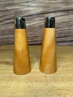 Pair of mid-century modern teak and chrome salt and pepper shakers, front view showing light wood grain and chrome tops.