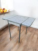 Table shown with both leaves extended, highlighting chrome legs with casters and patterned laminate top.