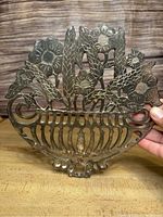 Front view of the 8-inch silver plated cast metal grape vine decorative wall art trivet, showing grapevine and flower cut-out design with a basket base.
