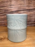 Front view of vintage blue ceramic pot with embossed bamboo leaves and stalk texture.