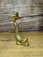 Side view of vintage brass koi fish wall decor placed on wooden surface showing detailed scales and tail fin with areas for hanging.
