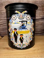 Full view of the vintage black metal tin with colorful Pennsylvania Dutch folk art depicting two figures in traditional clothing, a buggy, floral and bird motifs.