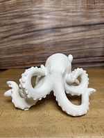 Front view of white ceramic octopus showing head and curling tentacles in detail.
