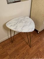 Front angled view showing faux marble triangle top and three gold metal hairpin legs