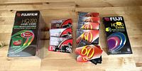 Photo showing 5 pack Fujifilm 10 Hour VHS tape sealed, 4 Maxell UR 90 minute cassette audio tapes sealed, 6 VCI 60 minute audio cassette tapes in cases, and one Fuji HQ 8 hour VHS tape sealed.