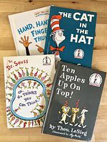 Four children's books including Dr. Seuss classics and a Theo LeSieg title, arranged on wood surface.