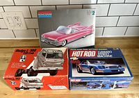 Overview of three model car kits in original boxes: Monogram Cadillac Eldorado, MPC Dodge L-700 cab, Hot Rod Camaro Street Machine. Boxes are open and show vintage illustrations.