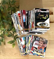 Photo showing large stacks of 1990s NASCAR collectible trading cards, including car images and driver portraits.