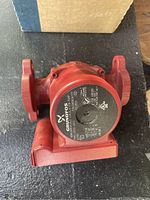 Red Grundfos UPS15-58FC pump showing faceplate with electrical and model specifications