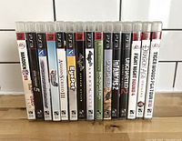 Photo showing 15 PlayStation 3 games lined up side by side, titles readable on spines.