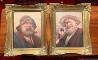Two framed prints side-by-side showing portraits of elderly men smoking pipes, in decorative gold-tone frames with wear.