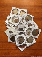 Overview of 25 vintage coins each in a white cardboard holder with handwritten notes around the edges. Coins vary in size and condition, showing signs of light use.