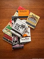 Top view of 11 vintage matchbooks stacked, showing mid-century designs from Ontario businesses including DeSoto, Motor Inn and others.