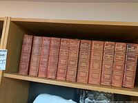 Shelf showing eleven volumes of The Makers of Canada 1912, red leather hardcover with gold embossed titles
