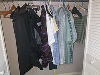 Closet showing black dinner jacket and pants along with men’s shirts in various colors and patterns hanging on hangers.