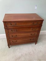 Front view of wooden dresser showing four drawers and brass handles