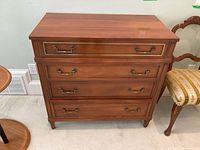 Front view of wooden Lionel Rawlinson four-drawer dresser showing brass handles and decorative trim