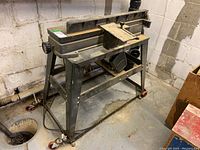 Side angled view of jointer/planer showing stand and work surface with cutter head enclosure.