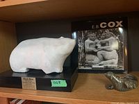 Bear sculpture, EB Cox book and small figurine on shelf