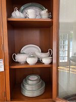 Cabinet view showing cups, saucers, serving platter, serving dishes, teapot, sugar bowl, creamer and gravy boat