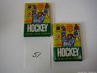 Two unopened 1990 Topps Hockey Jumbo Wax Packs with yellow and green packaging featuring an illustrated hockey player.