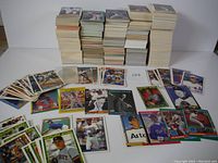 Stacks and piles of baseball cards spread out on a white surface showing front faces featuring various players and brands.