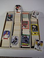 White cardboard box filled with stacks of hockey cards and sample cards displayed on top