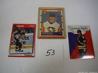 Three Jaromir Jagr hockey cards laid out on a flat surface with a numbered card '53'. Cards show Jagr in Penguins uniform, one in a rigid protective case.