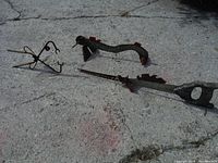 Photo showing three small scrap metal fish sculptures placed on concrete ground including one featuring a saw blade body, and two smaller wire and metal rod fish