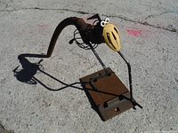 Full side view of metal bird sculpture cast in scrap metal with curved tail and flat base