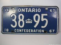 Full front view of blue 1967 Ontario license plate with white embossed characters and crown emblem