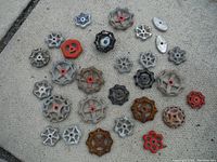 Top-down image showing 28 various vintage valve handles laid out on concrete surface, with mixed colors including red, black, silver, and rust.