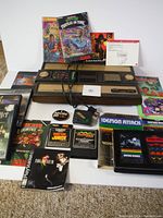 Overview of lot showing Coleco Intellivision console, assorted game cartridges, PS2 games, and instruction booklets.