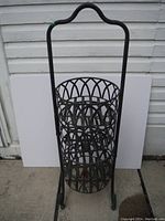 Full front photo of tall black metal plant stand with four round basket-style holders arranged vertically on the frame.