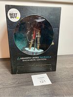 Full front view of figure packaging showing the Assassin's Creed Valhalla Ragnarok Edition Eivor vinyl figure sealed inside with visible packaging wear