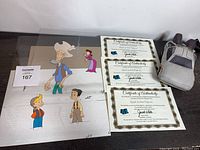 Photo shows animation sketches and plush toy alongside three Certificates of Authenticity for the Back To The Future artwork.
