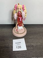 Front view of Beatrice figure in red dragon-patterned dress on round base