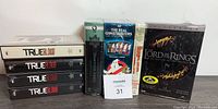 Five DVD and VHS collections including True Blood seasons 1-4, The Real Ghostbusters, The Lion King, and The Lord of the Rings Trilogy Extended Edition